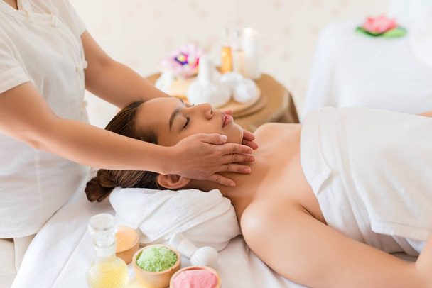 Hermosa chica asiática relajante recibiendo masaje facial en un salón de spa
 - Foto, Imagen