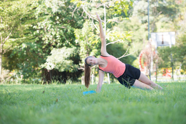 Junges Mädchen mit Yoga-Übungen im Freien im Park. Gesundheits- und Fitnesskonzept - Foto, Bild