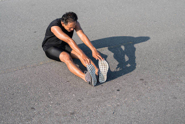 Erkek koşucu sabah koşuya hazırlanmak için bacak kasları germe. Sağlık ve fitness kavramı - Fotoğraf, Görsel