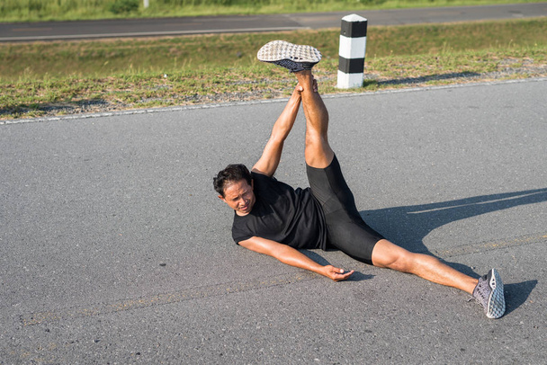 Erkek koşucu sabah koşuya hazırlanmak için bacak kasları germe. Sağlık ve fitness kavramı - Fotoğraf, Görsel