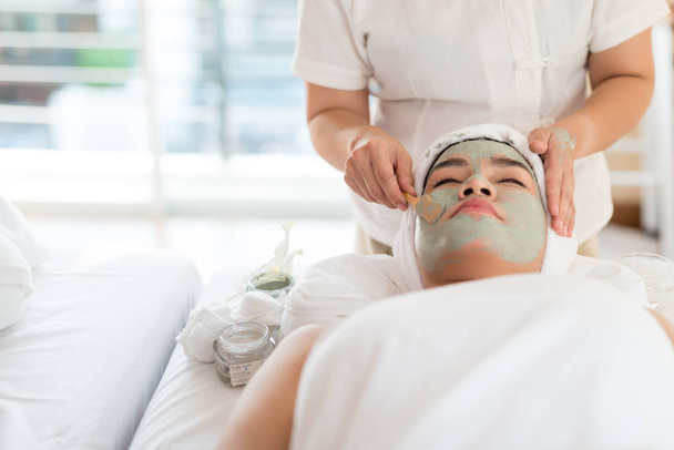Een vrouwelijke therapeut doet Facial Spa / Behandeling Voeg vocht toe aan de huid met Aziatische vrouw liggend op een bed in spa salon. - Foto, afbeelding