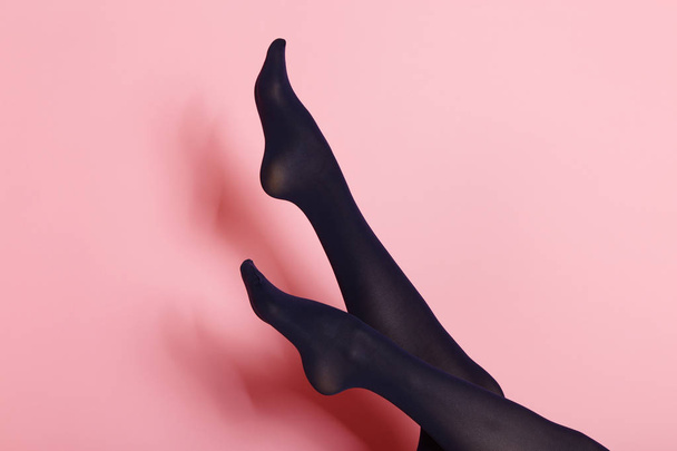 Legs of young caucasian woman in black tights on pink background - Photo, Image