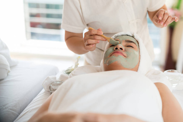 Une thérapeute qui fait du soin du visage Ajoutez de l'humidité à la peau avec une femme asiatique allongée sur un lit dans un salon de spa
. - Photo, image