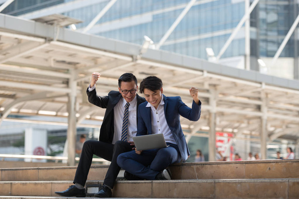 Succesvolle opgewonden Aziatische zakenmensen groep team aanbrengen samen en houdt van vuist ok ja gebaar in het zakelijke district achtergrond - Foto, afbeelding