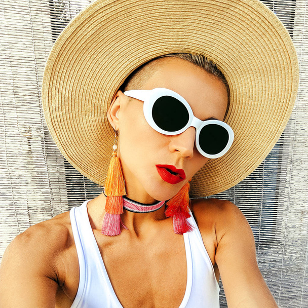 Girl in stylish beach accessories. Sunglasses, earrings, hat. Beach fashion outfit. - 写真・画像