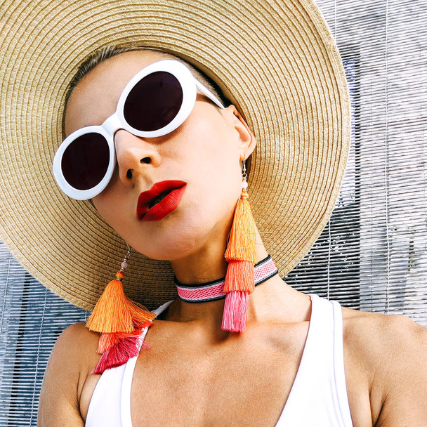 Lady in stylish beach accessories. Sunglasses, earrings, hat. Beach wear outfit. - Фото, изображение