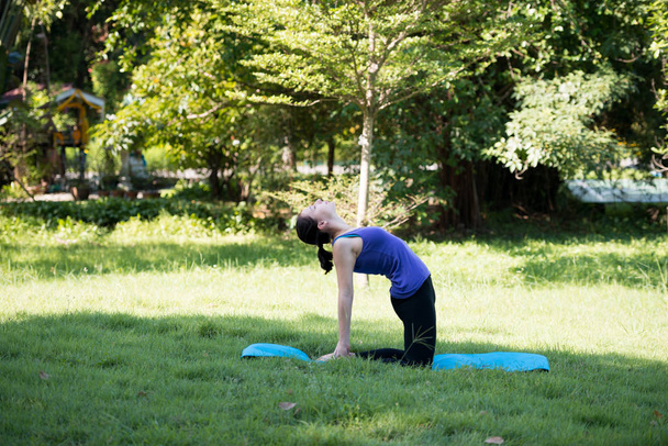 Young woman practicing yoga in the park outdoor. Concept of healthy lifestyle and relaxation. - Foto, Imagem