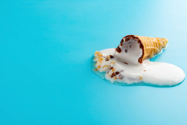 mini Vanilla flavor ice cream cone in a melting process on blue background - Фото, изображение