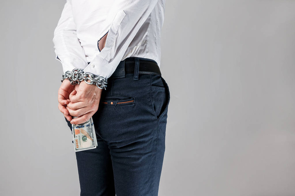 Hands of businessman with dollars prisoners in chains, handcuffs. The concept of combating corruption, bankruptcy, bail, crime, bribery, fraud, auction bidding - 写真・画像
