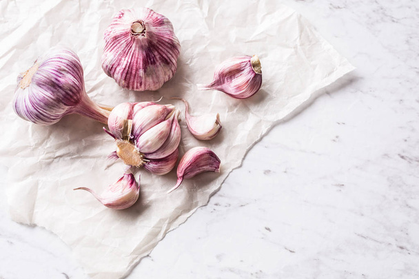 Garlic Cloves and Bulbs on white marble board. - Zdjęcie, obraz