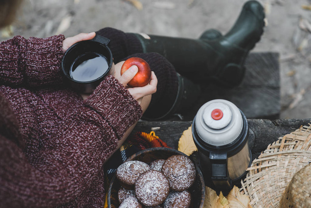 Top shot of woman in cozy sweater holding a cup with hot drink . Tea time outdoors. - Fotó, kép