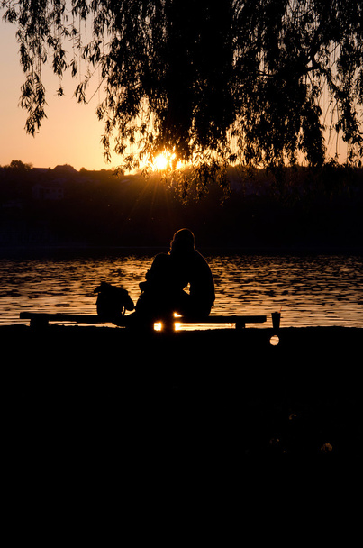 liefhebbers op de Bank door het meer tegen de ondergaande zon - Foto, afbeelding