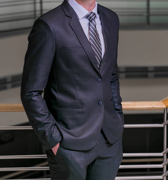 Elleri ceplerinde bir ofiste olan akıllı takım elbiseli kırpılmış kafa adam ayakta - Fotoğraf, Görsel