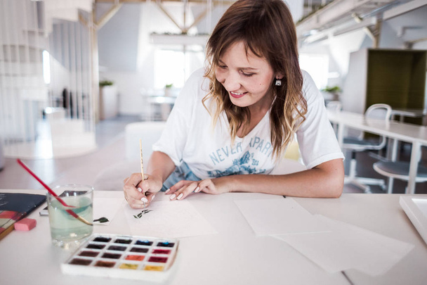  Καλλιτέχνης Σχεδιάστε μια εικόνα στο studio. Ζωγραφική όμορφη κοπέλα σε λευκό εσωτερικό - Φωτογραφία, εικόνα