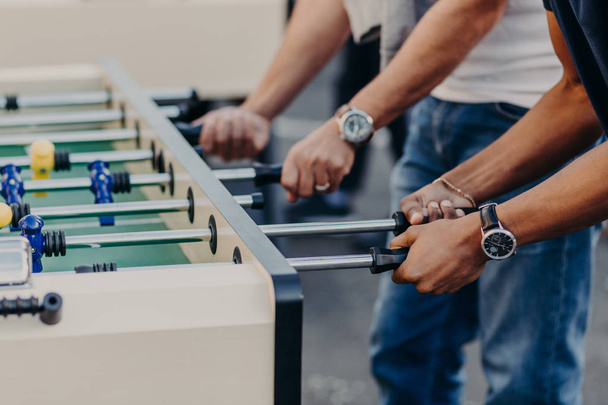 Cropped view of male`s hands play table football, enjoy recreation or leisure time during holidays, spend free time in bar. Competition concept - Φωτογραφία, εικόνα