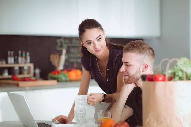 Couple paying their bills with laptop in kitchen at home - Fotografie, Obrázek