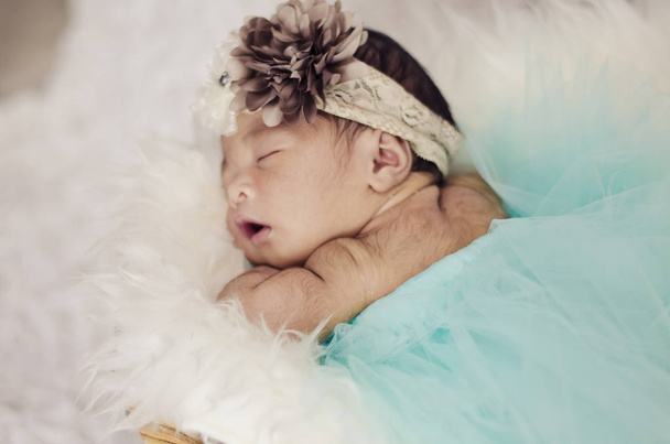 Portret van leuk en schattig pasgeboren baby met hoofdband slapen in de mand bedekt met harige mat.motherhood en ouderschap concept. - Foto, afbeelding