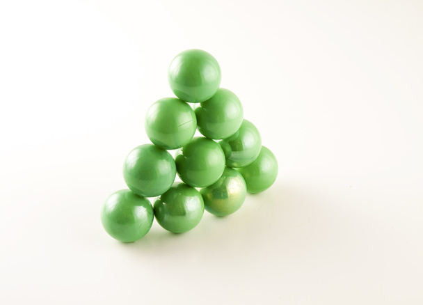 triangle of green marbles on a white background - Photo, Image