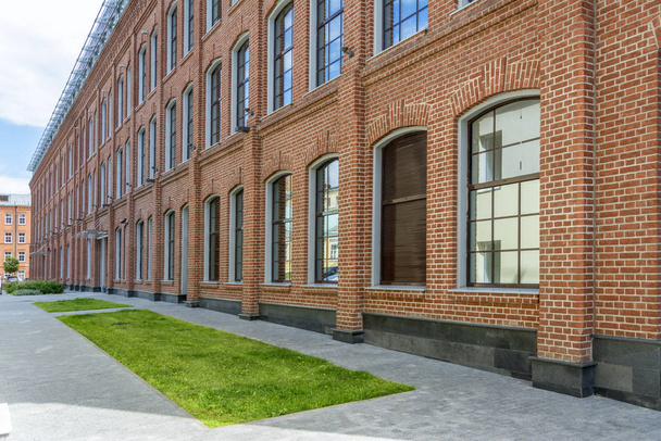 Office building in loft style. Large Windows. Red brick wall. Grass in front of the building - Foto, immagini