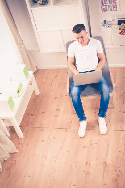 Young man sitting on chair with laptop - Foto, Imagem