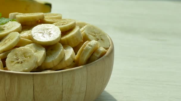 bananas fatiadas em tigela de madeira e bananas inteiras na mesa
  - Filmagem, Vídeo