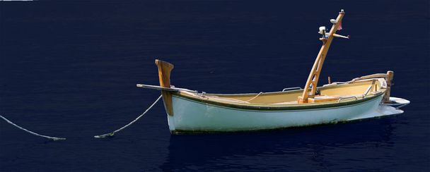 Un vieux bateau de pêche en bois amarré dans un petit port sur le fond bleu marine
 - Photo, image
