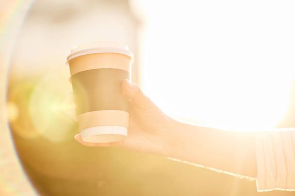 fiatal girl gazdaság papír csésze forró kávéval, naplementekor - Fotó, kép