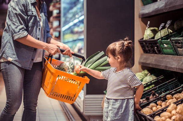 Mom and daughter are shopping at the supermarket, the concept of family relationships and healthy eating - Photo, Image