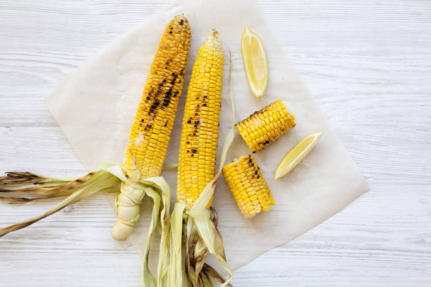 Grilled corn on the cob with slices of lemon, close-up. Summer food. Top view, from above, overhead. - Foto, afbeelding