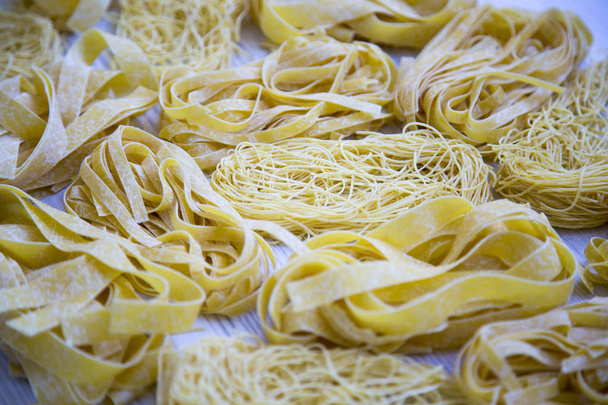 Joukko erilaisia kypsentämättömiä pastaa valkoisella puupöydällä, sivunäkymä. lähikuva-analyysi
. - Valokuva, kuva
