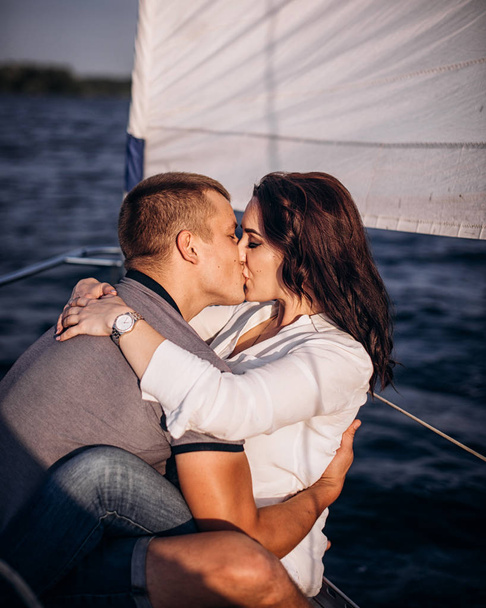 Пара в любові цілується на вітрильному човні посеред моря
 - Фото, зображення