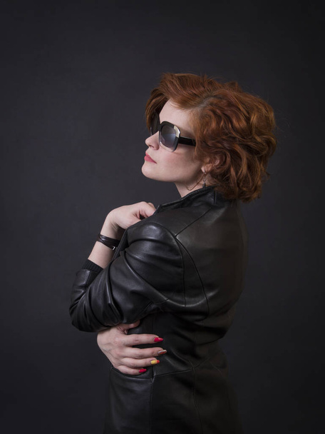 Emotional brunette posing in the Studio in a leather cloak.Isolated image on a dark background. - Fotografie, Obrázek