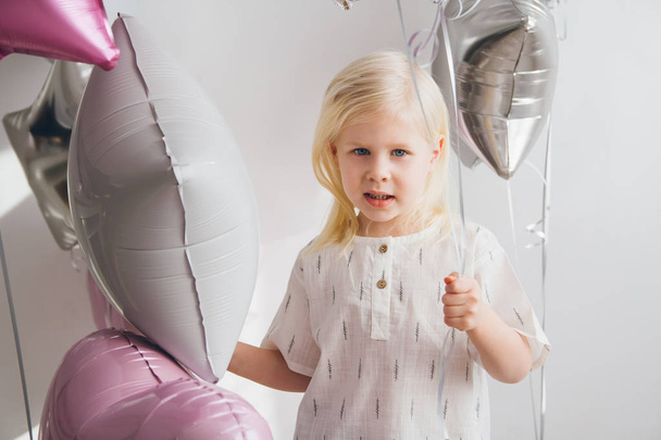 Happy little girl holding balloons. Celebration of the holiday. Toning. - Fotó, kép