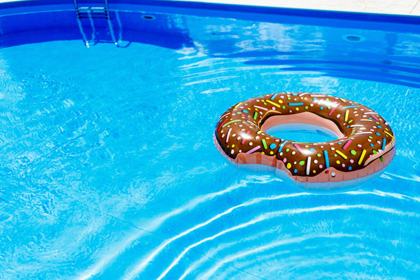 Felfújható gyűrű - fánk a kék víz a medencében. utazás, Nyaralás gyerekekkel, a nyári koncepció településen - Fotó, kép