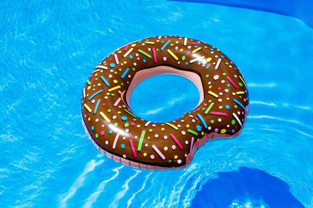 inflatable ring - donut in the blue water in the pool. travel, vacation with kids, holidays in the summer concept - Фото, изображение