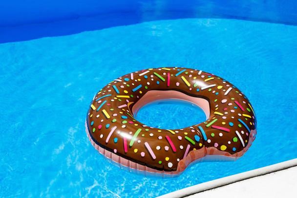 インフレータブル リング - プールで青い水の中のドーナツ。旅行、子供との休暇、夏のコンセプトの休日 - 写真・画像