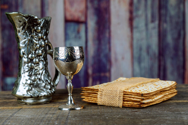 Red kosher wine with matzah a Passover Haggadah on a vintage wood background presented seder kiddush cup of wine - Photo, Image
