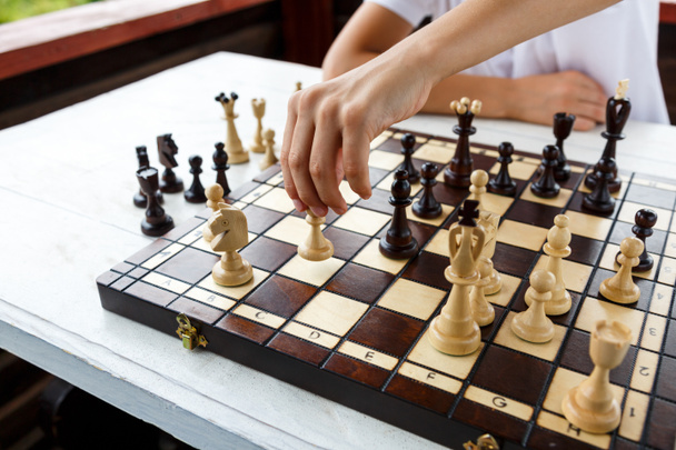 A mão do rapaz faz um movimento no tabuleiro de xadrez. Torneio de xadrez, acampamento, conceito de treinamento, Educação, lição de xadrez, jogo intelectual
 - Foto, Imagem