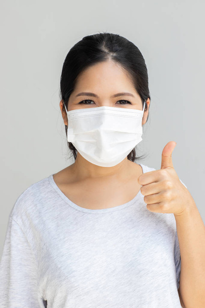Mulher asiática usando máscara facial polegar para cima
 - Foto, Imagem