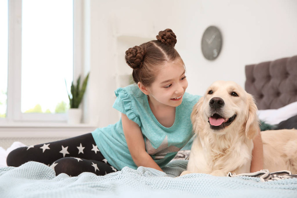 Cute little child with her pet on bed at home - Fotó, kép