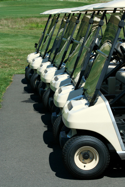 Vista frontal de una fila de carritos de golf
 - Foto, imagen