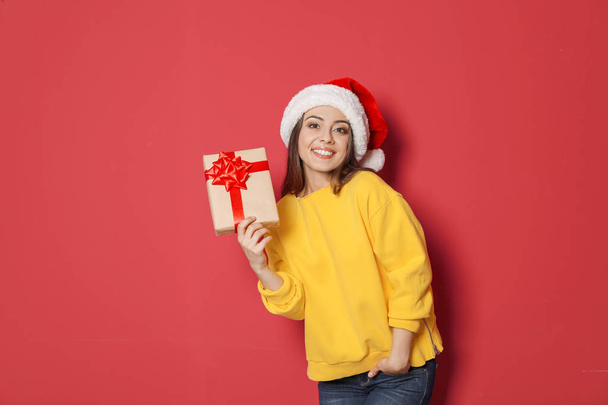 Young woman with Christmas gift on color background - Foto, Imagem