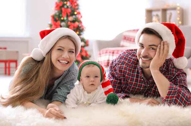 Happy couple with baby in Christmas hats at home - Fotó, kép