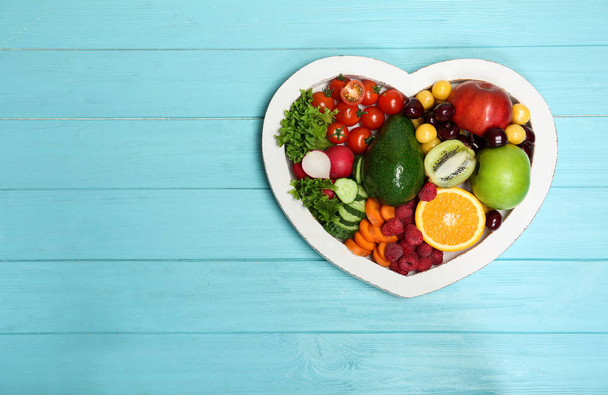 Heart shaped plate with fresh fruits and vegetables on wooden background, top view. Cardiac diet - Φωτογραφία, εικόνα