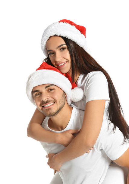Young happy couple with Santa hats on white background. Christmas celebration - Foto, imagen