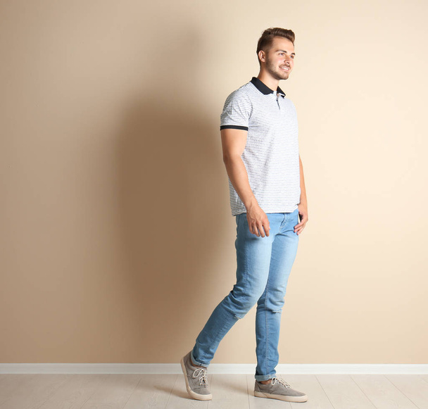 Young man in stylish jeans near light wall - 写真・画像