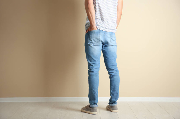 Young man in stylish jeans near light wall - Foto, Imagen