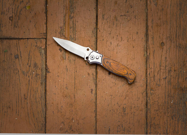 Knife on a brown wooden floor, murder, robbery - Fotó, kép