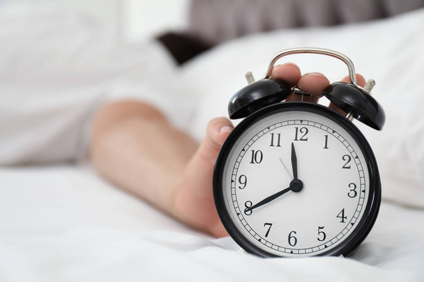 Man turning off alarm clock in bedroom - Zdjęcie, obraz