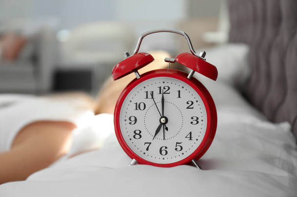 Analog alarm clock and blurred woman on background. Time of day - Zdjęcie, obraz